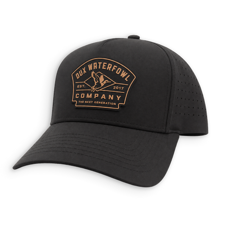A black hat with a curved brim, featuring a tan embroidered logo on the front that reads 'Dux Waterfowl Company' with a duck silhouette. The cap has perforated side panels for ventilation and is shown against a plain white background.