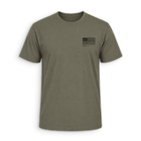 An olive green crewneck t-shirt with a small black distressed American flag graphic on the left chest, displayed on a clean white background.