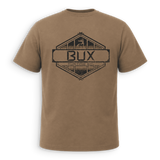 Back of tan crewneck t-shirt with black trim on the collar and sleeve cuffs, featuring a small black line-art deer logo on the left chest, displayed against a solid green background.