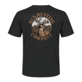 A black short-sleeve t-shirt shown from the back, featuring a large circular graphic print with a deer head, trees, and the text 'RUX HUNTING COMPANY' in brown and beige tones, set against a solid green background.