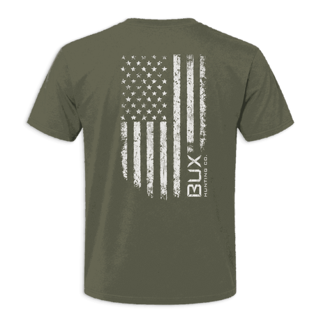 An olive green short-sleeve t-shirt shown from the back, featuring a distressed white American flag graphic with the vertical text 'BUX manufacturing CO.' printed on the right side of the flag.