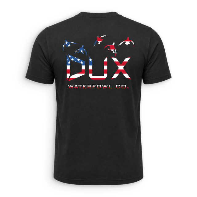 A black short-sleeve t-shirt shown from the back, featuring a large graphic print of the letters 'DUX' filled with an American flag pattern, with three waterfowl silhouettes above and 'WATERFOWL CO.' printed below.