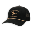 A black trucker hat with a curved brim, black mesh back, and tan embroidered logo and text reading 'DUX WATERFOWL CO.' and 'The Next Generation' on the front panel.