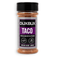 A bottle of Duxbux Taco Seasoning with a black cap and a gray and purple label, filled with brown seasoning, on a white background.