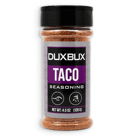 A bottle of Duxbux Taco Seasoning with a black cap and a gray and purple label, filled with brown seasoning, on a white background.
