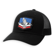 A black trucker hat with a curved brim and black mesh back panels, featuring a prominent shield-shaped patch on the front with a white eagle over a red, white, and blue background.