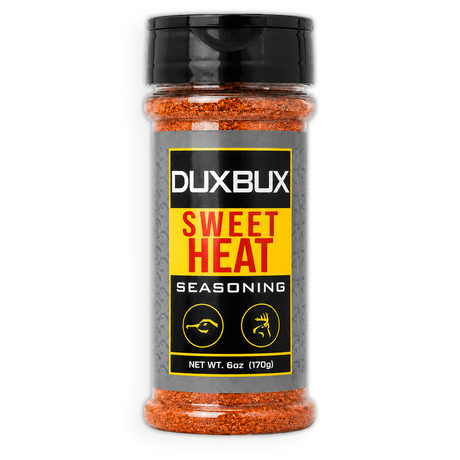A clear plastic shaker bottle of Duxbux Sweet Heat Seasoning with a black cap and a gray, yellow, and black label, filled with orange-red seasoning flakes.